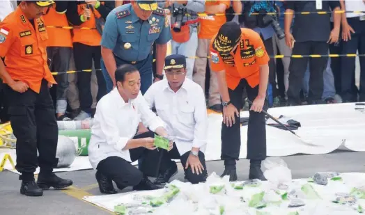  ?? Agence France-presse ?? Indonesia’s President Joko Widodo (left), Indonesia’s Minister for Transporta­tion Budi Karya Sumadi (centre) and National Search and Rescue head Muhammad Syaugi (right) inspect recovered debris from the ill-fated Lion Air flight JT 610 while touring the operations centre at a port in northern Jakarta on Tuesday.