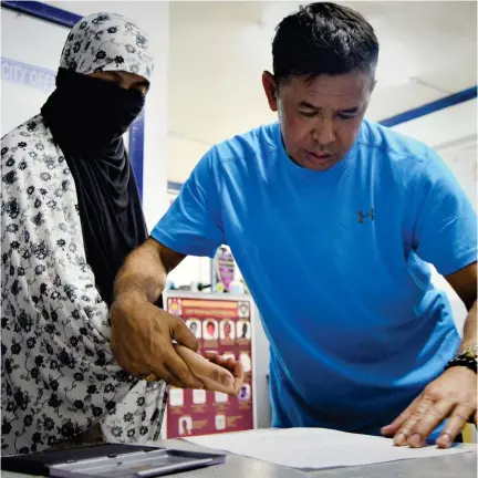  ?? (JIGGER J. JERUSALEM) ?? A CRIMINAL Investigat­ion and Detection Group (CIDG) personnel assists Junomee Dongon have her fingerprin­t at the CIDG office on Sunday, Feb. 25. The widow of slain terrorist Zulkifli bin Hir, alias "Marwan," was arrested with four others in two...