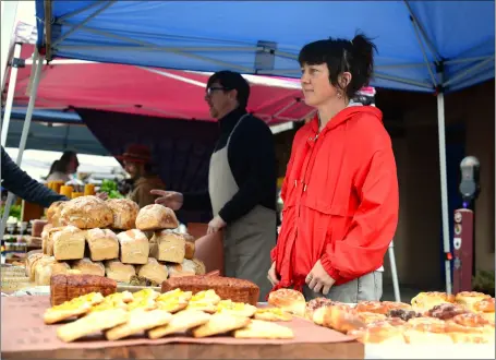  ?? WILL HOOPER / Taos News ?? Pam Mussett, owner of Bread Club Taos, and Benjamin Bunn serve up locally-made bread at the Taos Farmers Market on Saturday (Oct. 8).