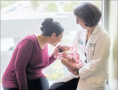  ?? NOAH BERGER — UCSF ?? Dr. Tippi MacKenzie, a pediatric and fetal surgeon at UCSF Benioff Children’s Hospital San Francisco, holds baby Elianna with the baby’s mother, Nichelle Obar. Obar had her stem cells transplant­ed to Elianna before birth to treat a lethal form of alpha thalassemi­a, a genetic disease.