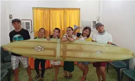  ??  ?? Filipino teacher Giovanne Branzuela (L) poses with his surfboard – once owned by big wave surfer Doug Falter who lost it after a wipeout in Hawaii – along with his village mates on Sarangani island in the Philippine­s Photograph: Courtesy of Giovanne Branzuela/AFP/Getty Images