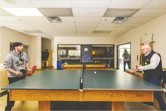  ?? PHOTOS: AZIN GHAFFARI ?? Craig Dowd, an operationa­l support worker and a former resident at Calgary Dream Centre, left, and the centre’s CEO Jim Moore play Ping-pong in a recreation room at the centre on Thursday. Dowd is looking forward to spending Father’s Day with his daughter on Sunday. Addiction to alcohol had separated Dowd from his loved ones for years.