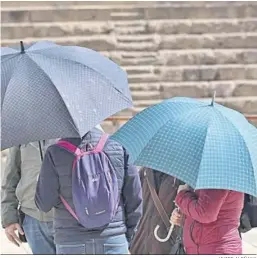  ?? JAVIER ALBÑANA ?? Varias personas se protegen de la lluvia con paraguas.