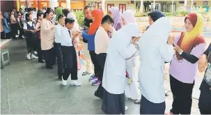  ??  ?? SEMOGA BERJAYA: Calon Ujian Pencapaian Sekolah Rendah, Sekolah Kebangsaan Dato Traoh di Kota Samarahan bersalaman dengan ibu bapa dan guru.
