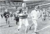  ?? VASHA HUNT/AP ?? Alabama quarterbac­k Tua Tagovailoa (13) jogs off the field after Tagovailoa threw five touchdown passes, ran for a score and could scarcely miss in the second half to lead the top-ranked Crimson Tide to a 52-21 victory over rival Auburn on Saturday.