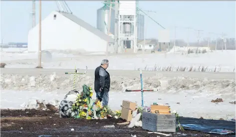  ?? JONATHAN HAYWARD/THE CANADIAN PRESS ?? Myles Shumlanski looks around a makeshift memorial at the intersecti­on of a fatal bus crash near Tisdale. Shumlanski’s son, Nick, was one of the survivors of last Friday’s crash, in which 16 people died. People have been coming from all over...