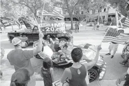  ?? JOHN MCCALL/SOUTH FLORIDA SUN SENTINEL ?? Participan­ts wave American flags during a car caravan protest Sunday in Delray Beach where people urged local and state leaders to reopen South Florida.