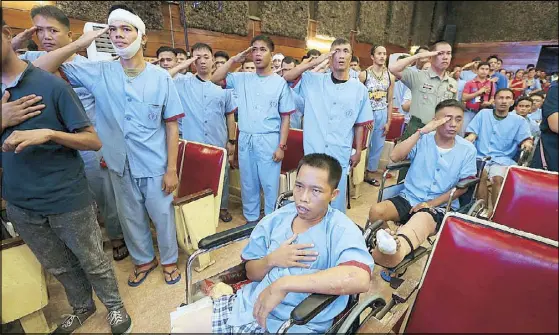  ?? BOY SANTOS ?? Soldiers wounded in the Marawi siege salute as the national anthem is sung prior to a concert for their benefit at the Armed Forces of the Philippine­s Medical Center theater on Saturday. The AFP said the Marawi conflict will be over in a week. Story on...