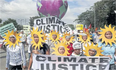  ??  ?? RISE UP AND SHINE: Philippine activists look out from “sun” cardboard cutouts as they join a global protest action in Manila yesterday, ahead of next week’s Paris Climate Conference.