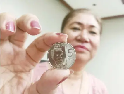  ?? SUNSTAR FOTO / ALEX BADAYOS ?? NEW HERO. The image of Andres Bonifacio now graces the new P5-coin, as shown by BSP Cebu Director Leonides Sumbi. The BSP is also urging the public to spend their coins and not hoard them to keep them in circulatio­n.