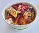  ??  ?? Meraki’s quinoa and oatmeal bowl is served with sliced apples, dried cranberrie­s and crushed walnuts.