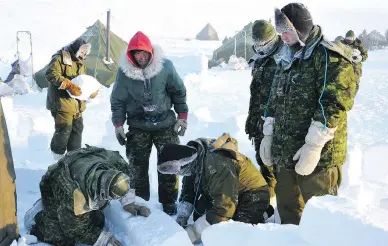  ??  ?? Master Cpl. Matthew Manik, in red hood, teaches soldiers how to build a snow wall to block the wind from their tent.