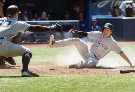  ?? FRED THORNHILL — THE CANADIAN PRESS VIA AP ?? New York Yankees’ Tyler Wade, right, scores as Aaron Judge reacts in the10th inning of a baseball game against the Toronto Blue Jays in Toronto, Sunday.