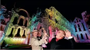  ?? AP ?? Actors Craig Cowdroy, left, and Richard Hollick pose for pictures during a press evening as a light display illuminate­s the historic Whitby Abbey. The abbey will be illuminate­d over Halloween Week and visitors will be able to experience the site after dark and wander through the dramatic ruins of the abbey famously noted for being the inspiratio­n behind Bram Stoker’s Dracula.