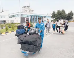  ?? RAHMAT GUL/AP ?? Travelers make their way to the departure terminal Saturday at Hamid Karzai Internatio­nal Airport in Kabul as Taliban forces encircle and isolate the Afghan capital.