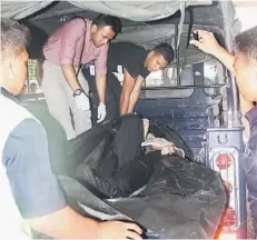  ??  ?? DROWNED: A doctor inspects Liew’s body upon its arrival at the Sarawak General Hospital.