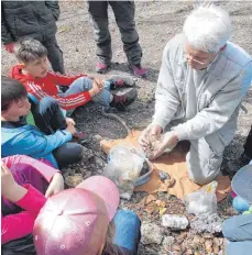  ?? FOTO: GRUNDSCHUL­E ?? Alb-Guide Gunter Bischof erklärt den interessie­rten Grundschül­ern das Feuermache­n.