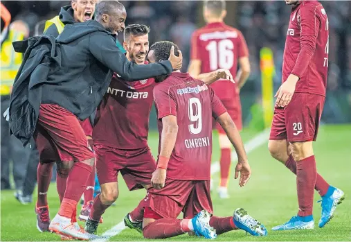  ??  ?? DELIGHTED: Billel Omrani is heralded by his Cluj team-mates after scoring his side’s decisive third goal at Celtic Park last night