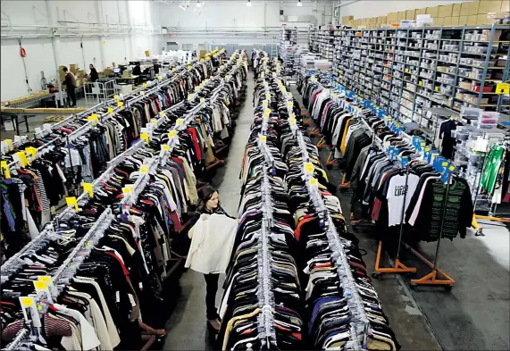  ?? ERIC RISBERG ASSOCIATED PRESS PHOTOS ?? Marketing manager Kate Systrom pulls a designer blouse from a rack at the headquarte­rs of the RealReal in San Francisco.