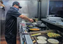  ??  ?? Jose Luis Salazar cooks orders for customers at Cheliz Restaurant last summer. Family members have helped the family business.