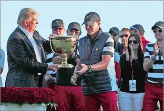  ?? JULIO CORTEZ/AP PHOTO ?? President Donald Trump, left, presents the winner’s trophy to U.S. Team Captain Steve Stricker on Sunday after the final round of the Presidents Cup at Liberty National Golf Club in Jersey City, N.J.