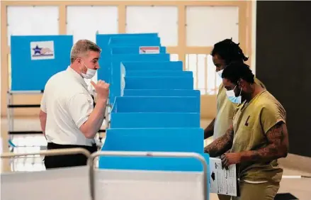  ?? Charles Rex Arbogast/Associated Press ?? Cook County Correction­s Sgt. Robert Mulac talks with inmates at the jail as they vote in the local election at the Division 11 chapel on Feb. 18 in Chicago.