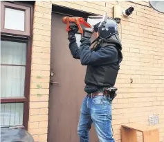  ?? ?? Busted An officer forces his way into a home during a recent raid