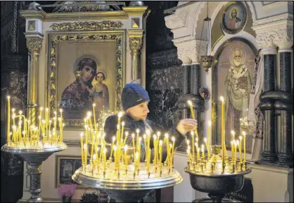  ?? EFREM LUKATSKY / AP ?? A woman lights candles for peace in St. Volodymyr Cathedral in Kiev on Thursday. Leaders of Russia, Ukraine, France and Germany announced a comprehens­ive peace deal for eastern Ukraine, but questions remained whether Ukraine and the pro-Russian rebels...