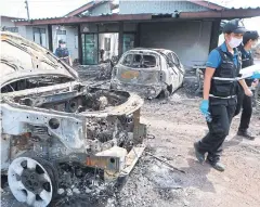  ?? SOMCHAI POOMLARD ?? Burned out cars and houses are seen near the site of Thursday’s gas pipe explosion in Samut Prakan’s Bang Bo district yesterday.