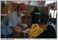  ?? (The New York Times/Joao Silva) ?? Jacqui Dallimore, a research nurse, vaccinates a volunteer in the Johnson & Johnson vaccine trial in December in Masiphumel­ele, South Africa. The one-shot coronaviru­s vaccine provides strong protection against severe covid-19, U.S. regulators said in an analysis released Wednesday.