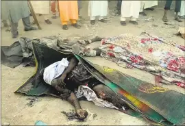  ?? THE ASSOCIATED PRESS ?? In this image taken from TV, people stand around dead bodies after a deadly attack by a suicide bomber at a mosque in Mubi, Adamawa State, Nigeria, on Tuesday. A teenage suicide bomber detonated as worshipper­s gathered for morning prayers, killing at...