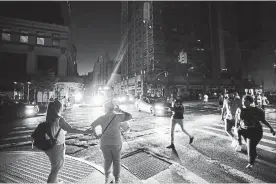  ?? MICHAEL OWENS THE ASSOCIATED PRESS ?? Pedestrian­s cross a dark street during a power outage Saturday in Manhattan.