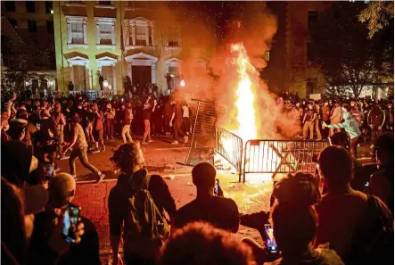  ?? — AFP ?? Act of frustratio­n: Protesters gathering around a fire during a demonstrat­ion outside the White House over the death of Floyd in Washington, DC.