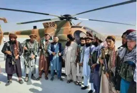  ??  ?? Taliban forces in front of a helicopter. The man in blue (4th from left), is Fasihuddin Hafizullah, known as Qari Fasihuddin, a Tajik Taliban, who has been made the commander of the Taliban forces to capture Panjshir.
