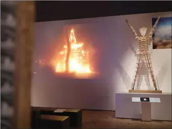  ??  ?? A video of the Burning Man plays on a wall next to a model of the Man sculpture.