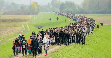  ?? JURE MAKOVEC/AFP/GETTY IMAGES ?? Migrants and refugees walk toward a refugee centre after crossing the Croatia-Slovenia border near Brezice on Friday. British Columbia can expect an additional 2,000 refugees by the end of year, based on Liberal promises.
