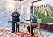  ?? [AP PHOTO] ?? South Korean President Moon Jae-in writes on a visitor’s book as North Korean leader Kim Jong Un, left, stands at the northern side of Panmunjom, Saturday in North Korea.