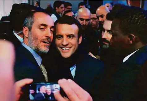  ?? AFP ?? French presidenti­al election candidate for the ‘En Marche’ movement Emmanuel Macron (centre) poses for a selfie during a meeting in Saint-Priest-Taurion, central France.