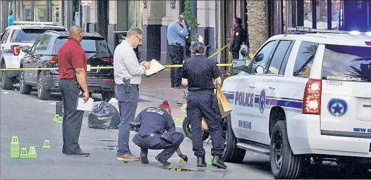  ??  ?? AFTERMATH: Police tape and bullet markers dot New Orleans’ Canal Street early Sunday after a still-at-large shooter wounded 10 people, two critically.