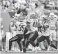 ?? AARON DOSTER/AP ?? Dolphins wide receiver Kirk Merritt tries to leap over Bengals cornerback Jalen Davis, left, and defensive back Brandon Wilson during Sunday’s game in Cincinnati.