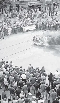  ?? FOTO: DPA ?? Düsseldorf, 12. Juni 1968: Was nach Gewaltexze­ss aussieht, ist vorerst nur ein drohendes Happening. Studenten zünden ein mitgebrach­tes altes Auto auf der Kö an, um gegen die Bildungspo­litik zu demonstrie­ren. Dazu rufen sie: „Heute Auto, morgen...