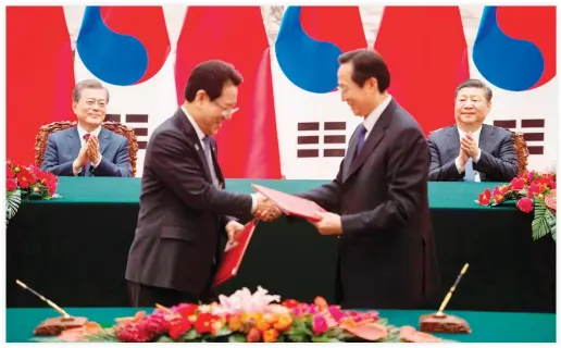  ??  ?? South Korean President Moon Jae-In, left, and Chinese President Xi Jinping, right, applaud during a signing ceremony at the Great Hall of the People in Beijing on Thursday. (AFP)