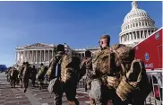  ?? ANDREW HARNIK/ASSOCIATED PRESS ?? Members of the National Guard walk past the Capitol Building in Washington on Jan. 14. Some 21,000 of them are in the city to protect against potential threats.