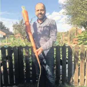  ??  ?? Pictured is Simon Smith with his monster 4ft carrot.