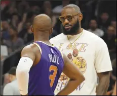  ?? Associated Press ?? Lakers forward LeBron James talks with Suns guard Chris Paul (3) during the first half on Tuesday in Phoenix. The Lakers lost 121-110 to the Suns and were eliminated from playoff contention.