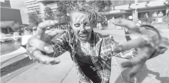  ??  ?? Playing dead came naturally to participan­ts such as Evelyn Jordan, whose antics attracted a crowd of photograph­ers at the start of the Victoria Zombie Walk in Centennial Square.