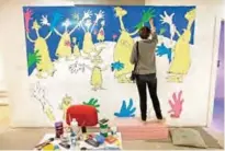  ??  ?? Cortney Thibodeau paints a mural based on artwork from the Dr Seuss book "Oh, The Thinks You Can Think!" at The Amazing World of Dr Seuss Museum.