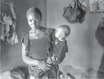  ?? JEROME DELAY/AP ?? Anayo Mbah, 29, holds one of her children in her home in Umuida, Nigeria, on Feb. 11. Mbah delivered her sixth child the same day she learned her husband died of COVID-19. His family stopped supporting her and sent her away weeks later.