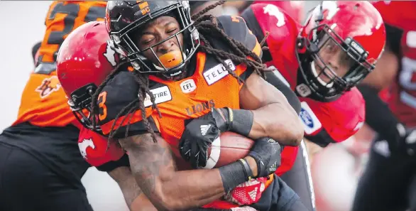  ?? JEFF McINTOSH/THE CANADIAN PRESS ?? The Lions’ Tyler Davis is tackled by the Stampeders in Friday’s exhibition game at Calgary’s McMahon Stadium, where the Lions won 36-23.