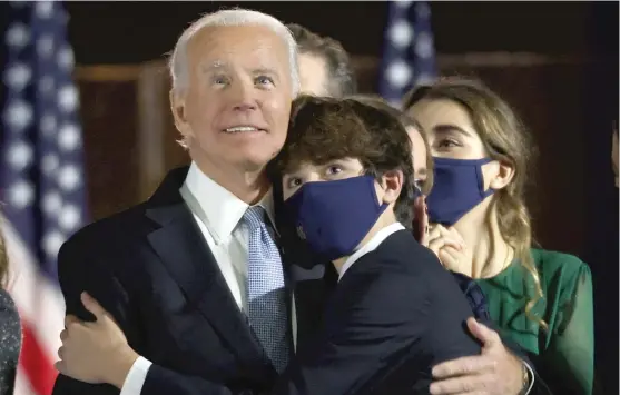  ?? WIN MCNAMEE/ GETTY IMAGES ?? President- elect Joe Biden hugs one of his grandchild­ren Saturday after his address to the nation in Wilmington, Delaware.